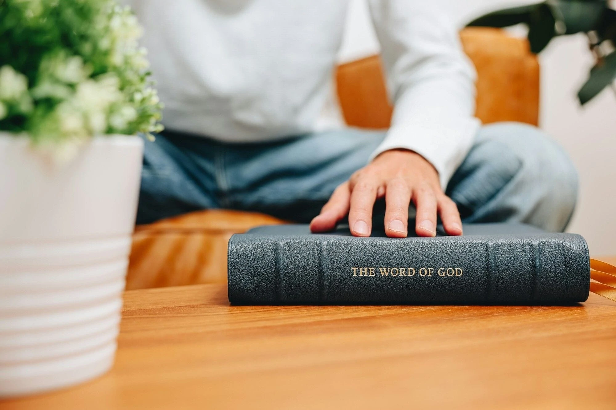 A picture of a hand placed on top of a bible.  The Bible says "The Word of God" on the spine.